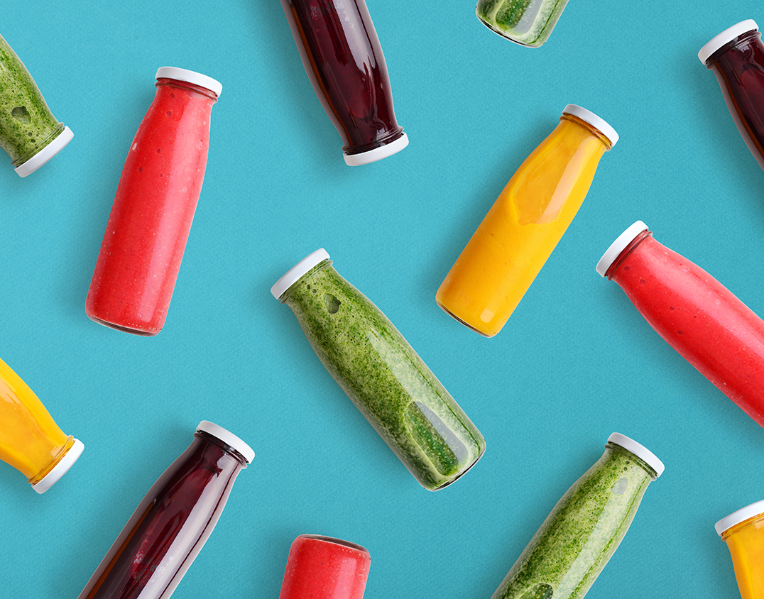 Colorful smoothies in glass bottles on blue background, top view.