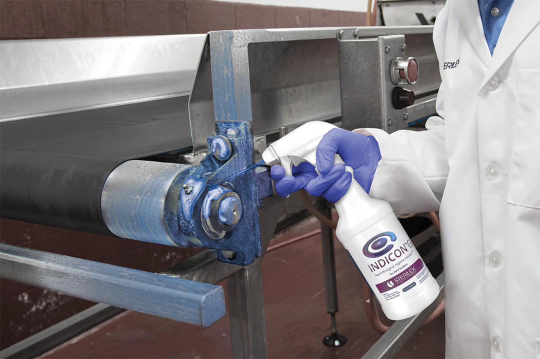 worker spraying Indicon Gel product onto conveyor