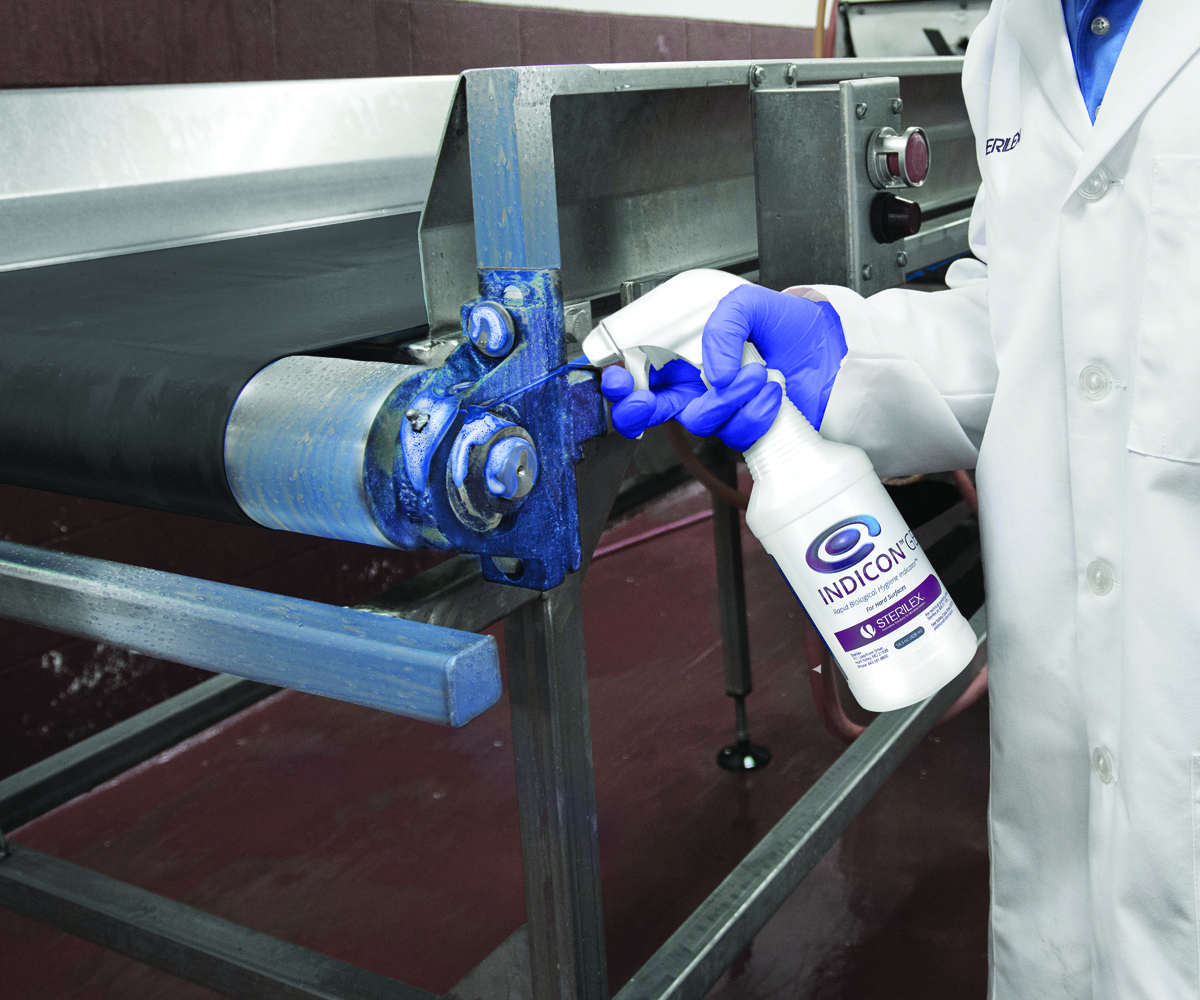 worker spraying Indicon Gel product onto conveyor